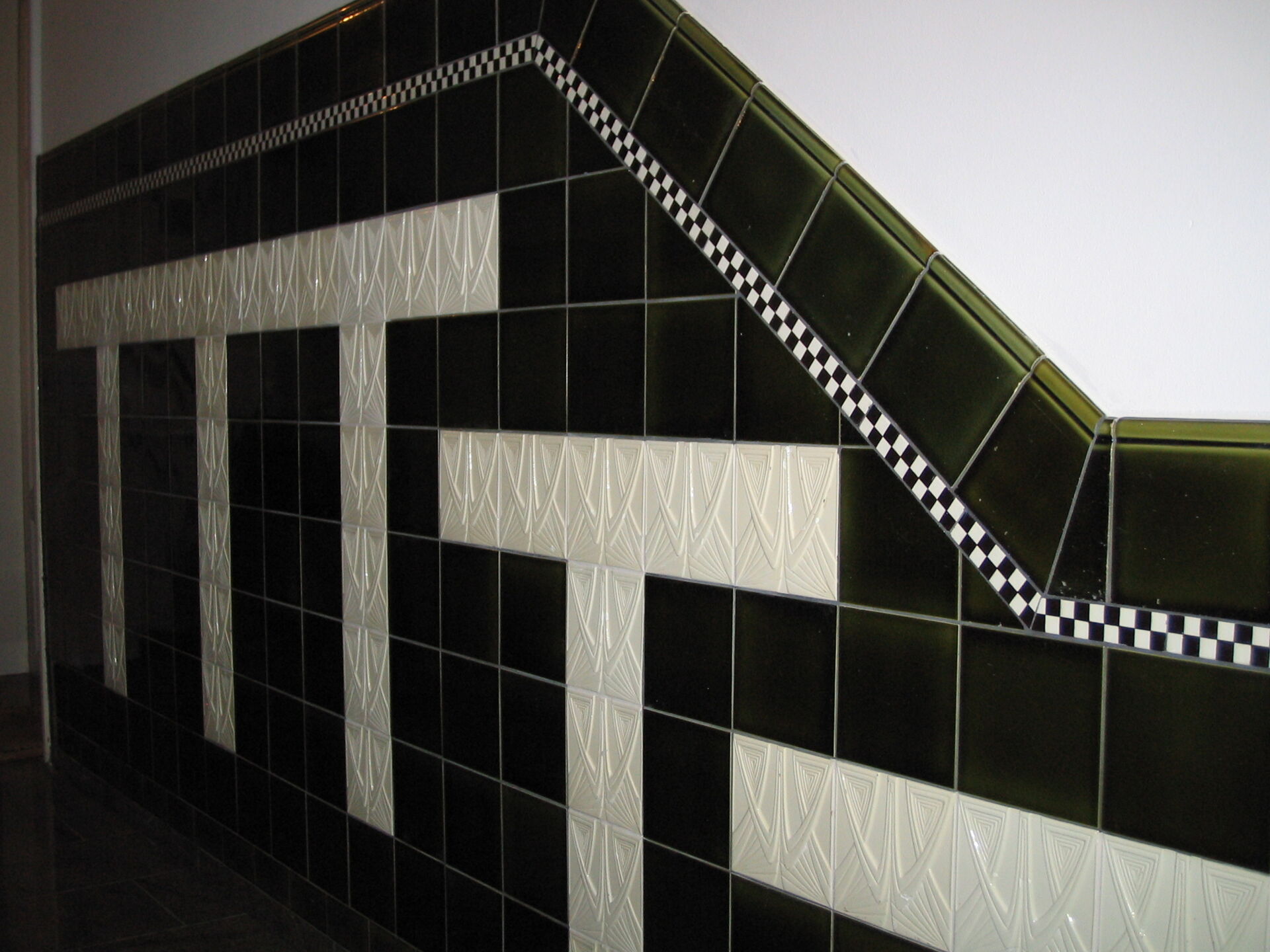 Ein Treppenaufgang mit einem auffälligen Fliesenmuster in Schwarz, Weiß und Schachbrettoptik, gestaltet vom Fliesenfachbetrieb Behnisch GmbH in Pulsnitz.